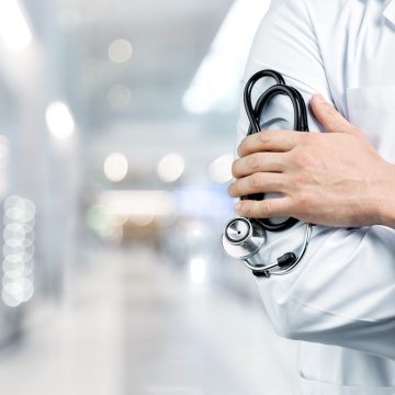 Doctor with a black stethoscope on hospital background